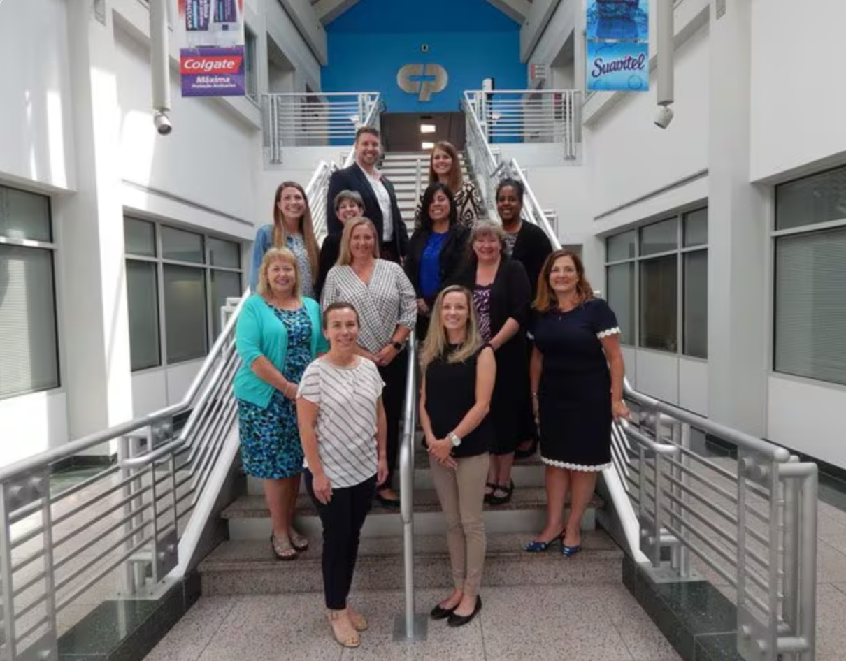 Group of people standing on stairs with Colgate logo visible in the background
